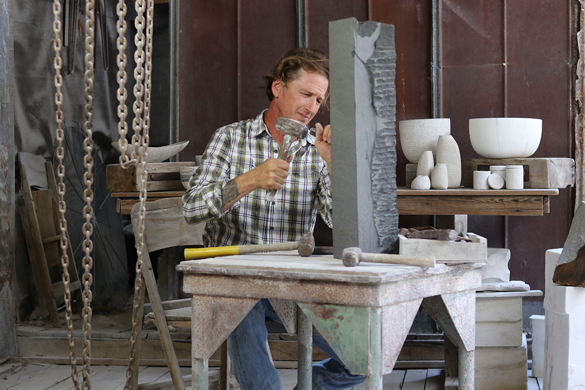 Brooks Barrow in his studio chiseling a sculpture. 