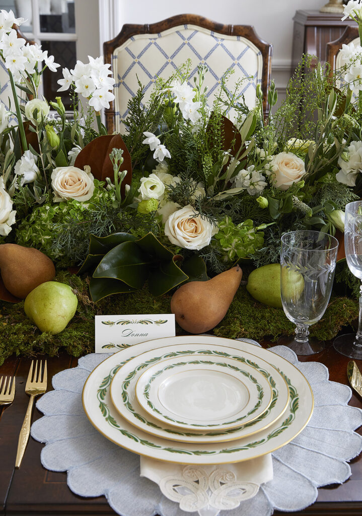 Table setting of cream plates with green details and gold utensils   