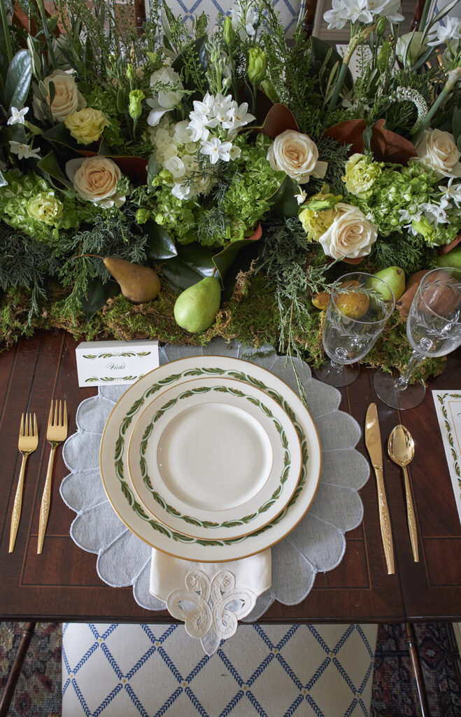 Table setting of cream plates with green details and gold utensils