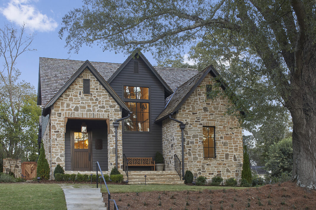 Exterior elevation photo of a cottage style home. Finished with large stone bricks and charcoal colored siding.