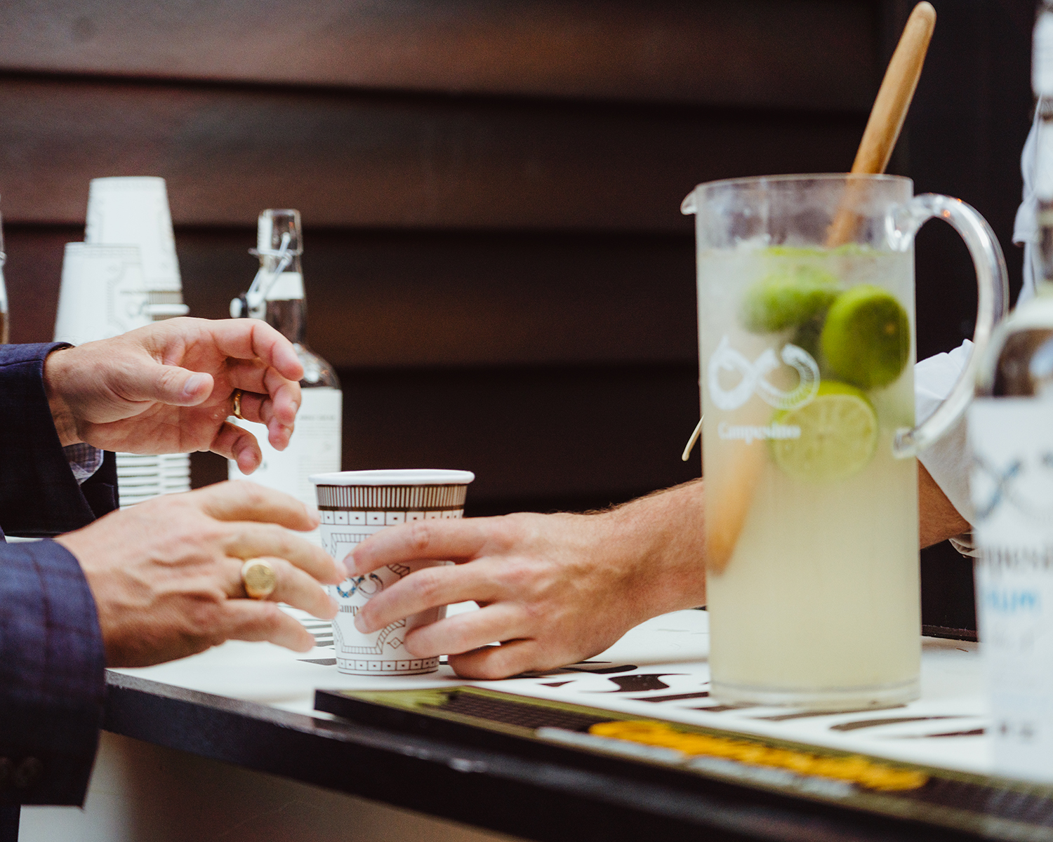 Hands sliding a fresh drink across the bar. 