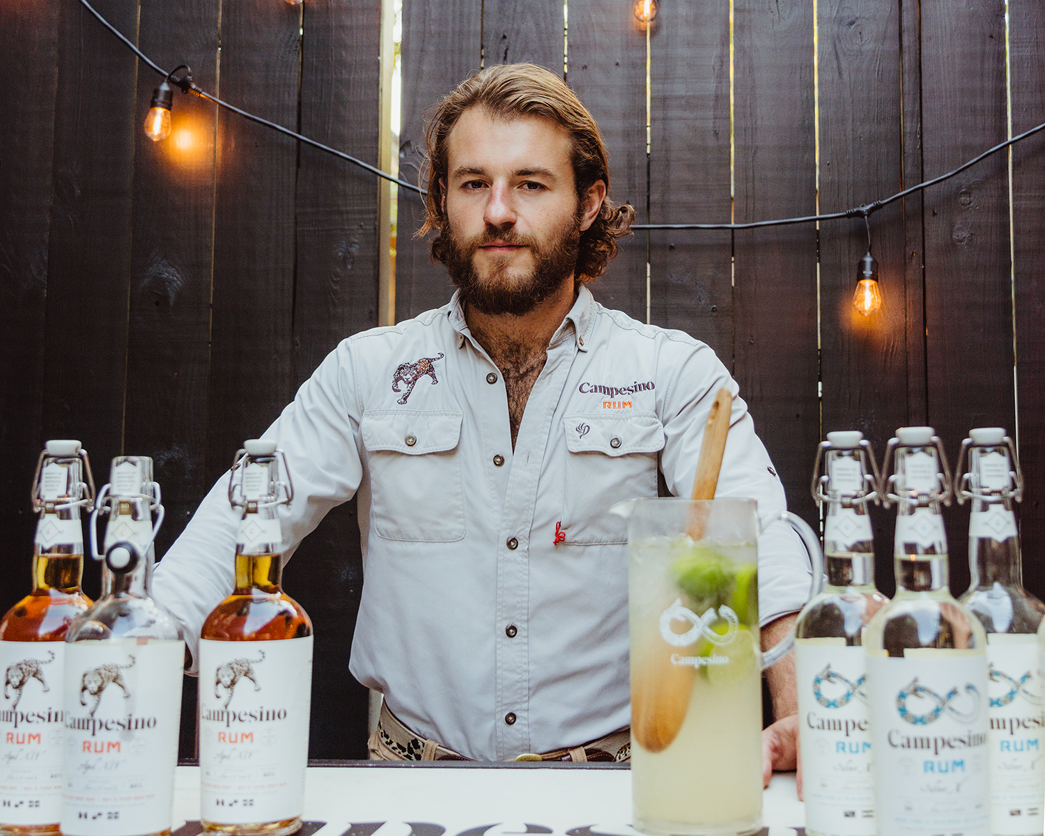 Hatton Smith II standing behind a bar filled with Campesino rum bottles and a pitcher of Campesino Lime Classico.