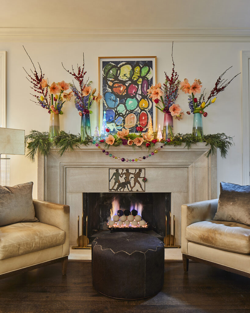 fireplace with bright artworks and flowers above the mantel