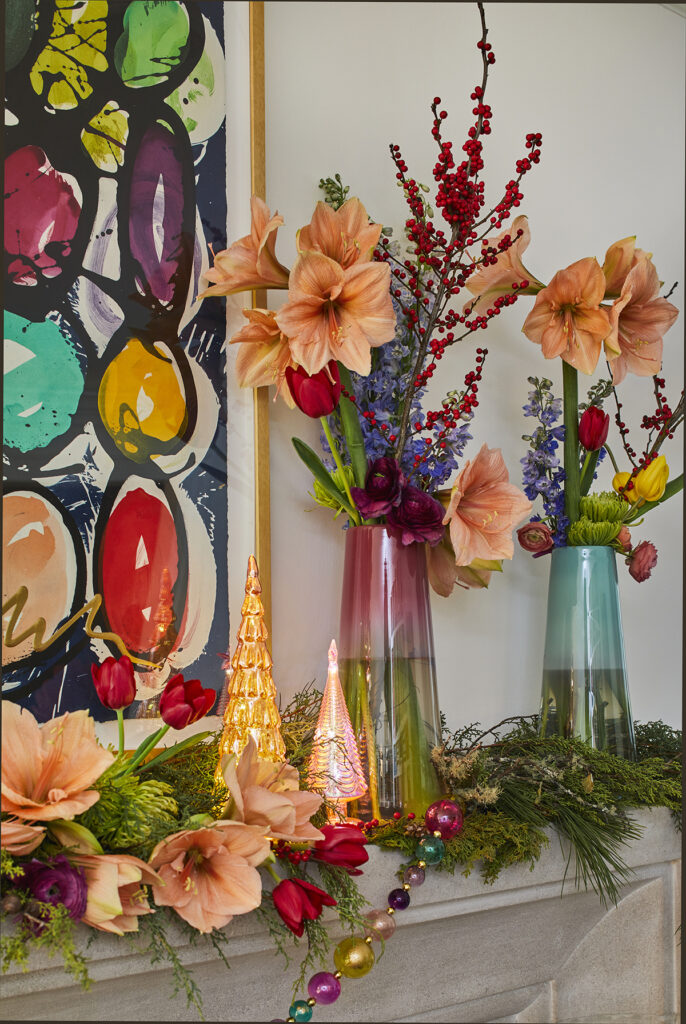 colorful flowers and stems in colored glass vases on mantel