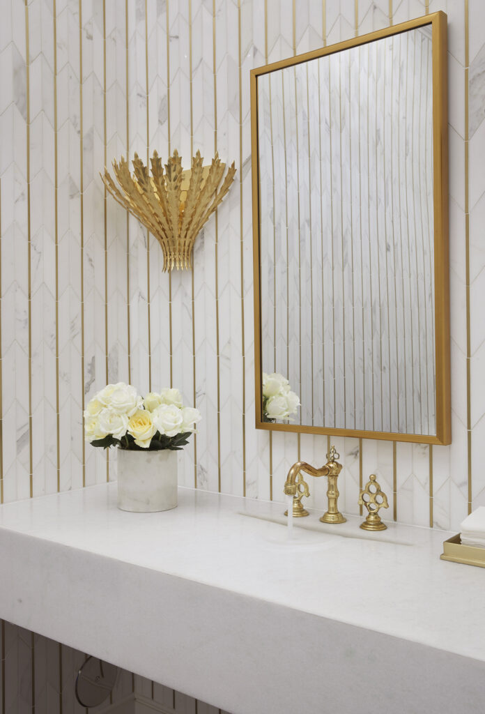 Bathroom sink surrounded by wall tile and gold accents.
