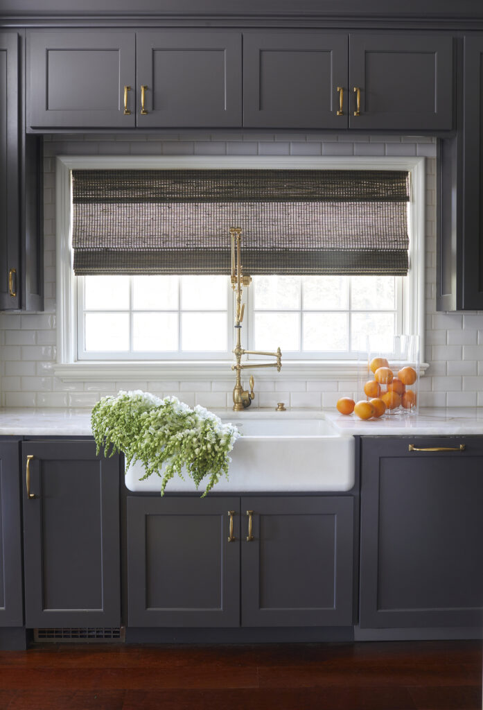 dark kitchen cabinets surrounding a white farm sink in front of a window