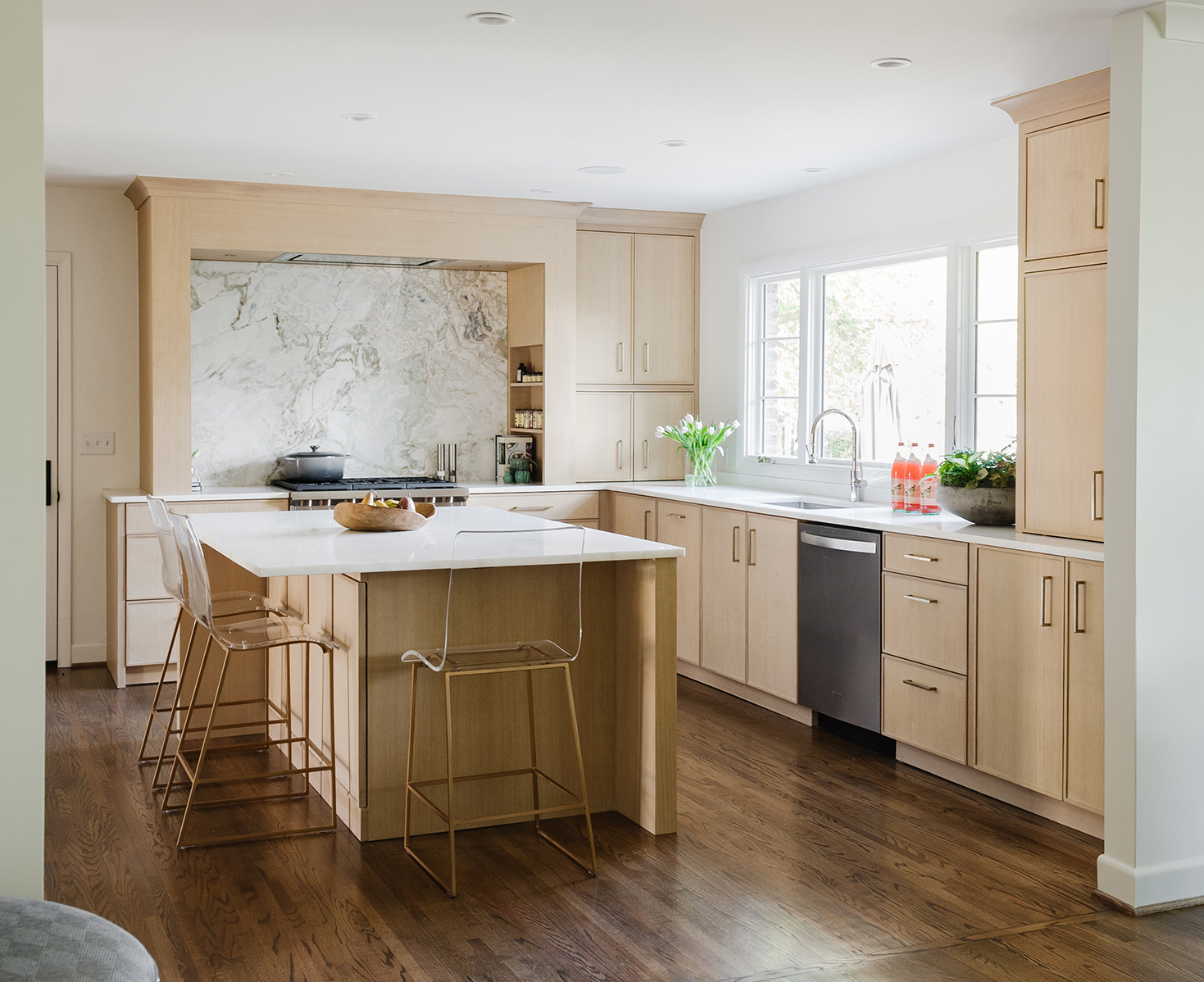 Light and airy kitchen with light wood cabinets and marble countertops and backsplash