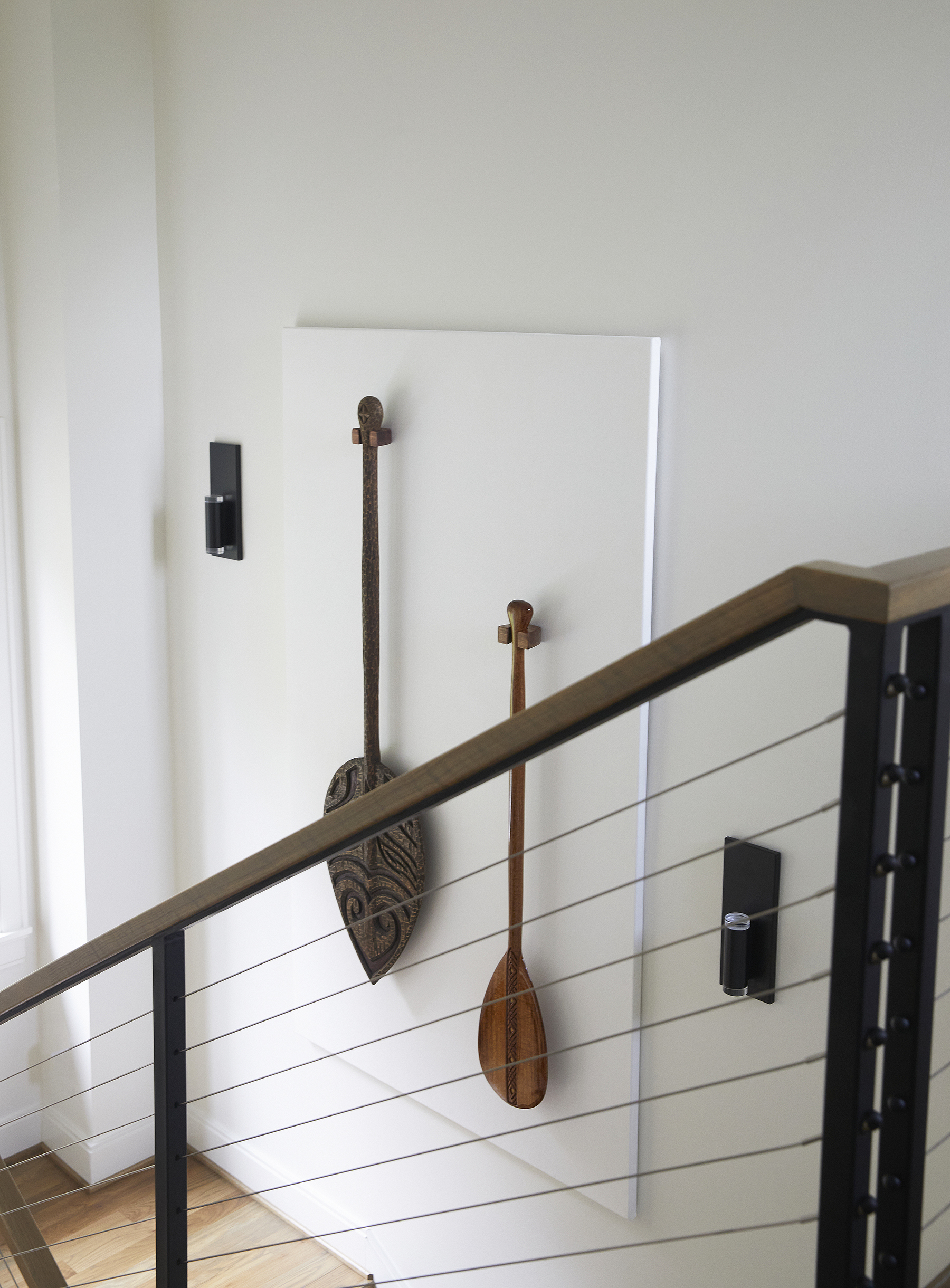 Two wooden artfully carved oars are hung on the wall next to the staircase