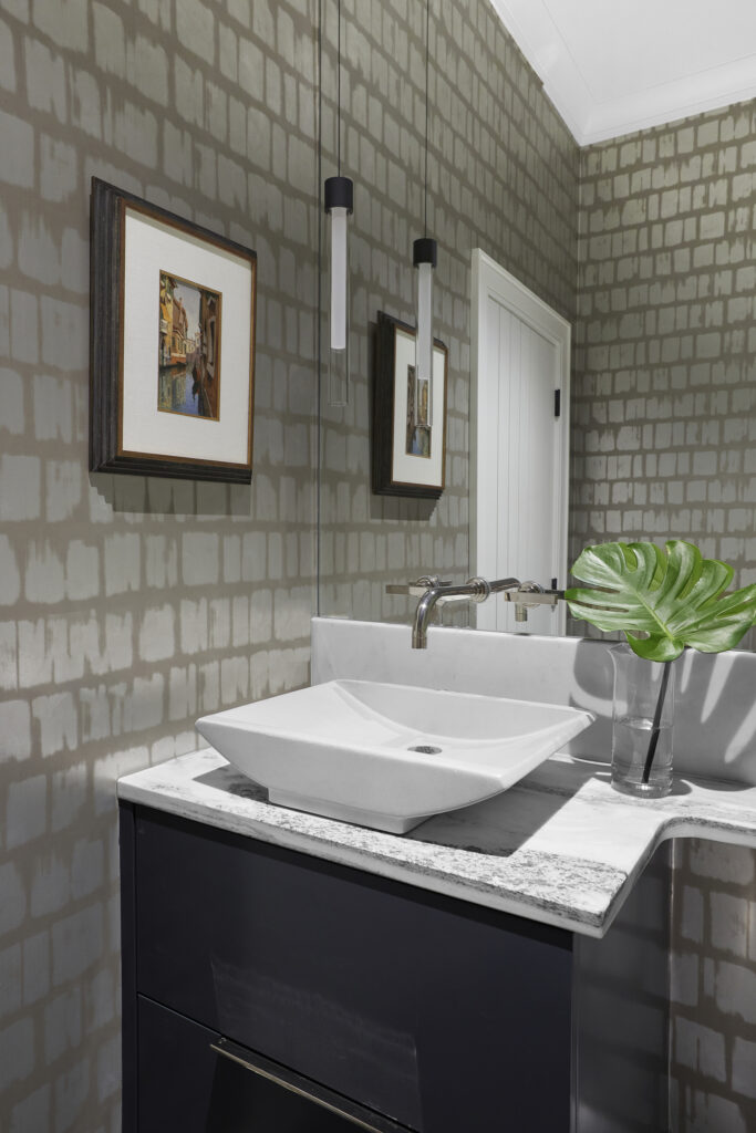 Half Bath with simple features, statement wallpaper, and art framed and hung beside sink.