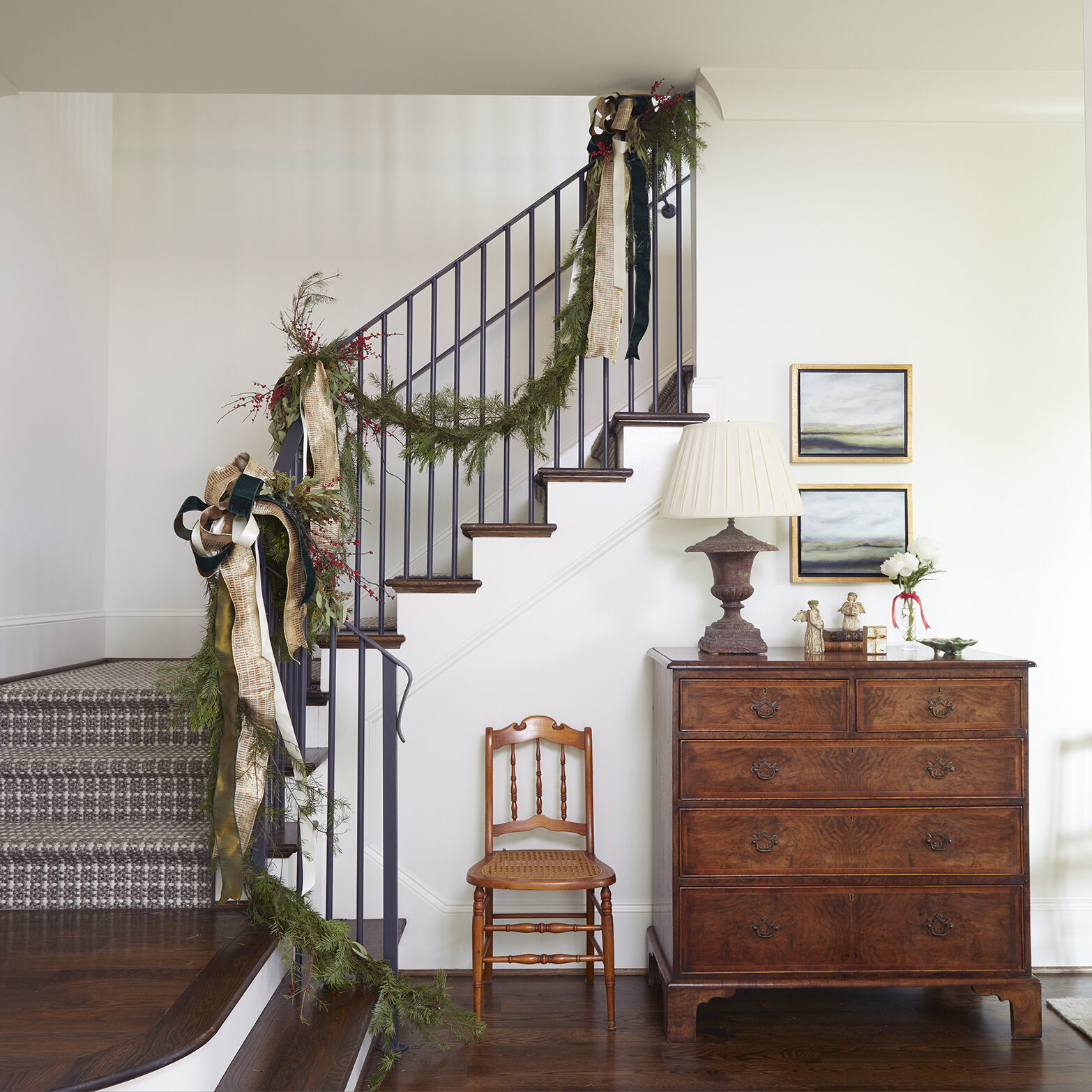 Wrought iron stairway is trimmed in garland accentuated with red berries and green and gold ribbon.