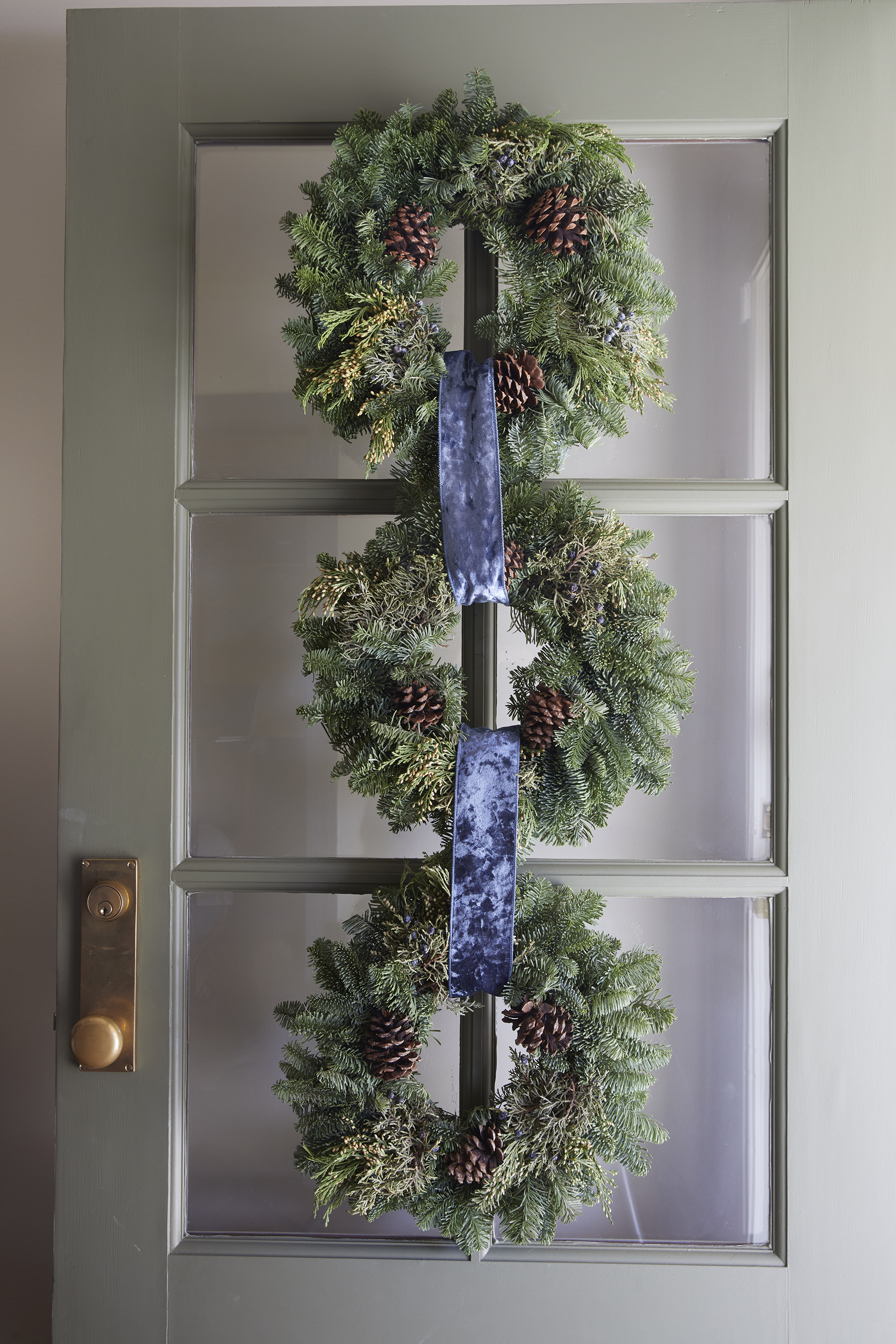 Three wreaths looped together with blue velvet ribbon hung on the front door.