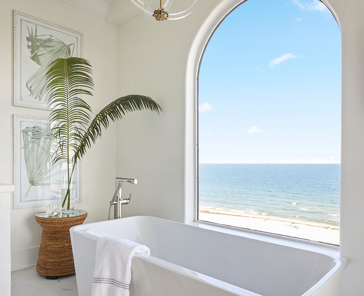 Bathroom with a freestanding spa tub 
under the arched window and a glass-enclosed shower